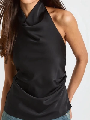 Svart halterneck linnetopp i satin - Snygg svart linnetopp med halterneck och draperad halsringning. Tillverkad i glansigt satinmaterial som ger en lyxig känsla. Toppen är ärmlös och har en figurnära passform som framhäver axlarna. Från zara mindre i stl