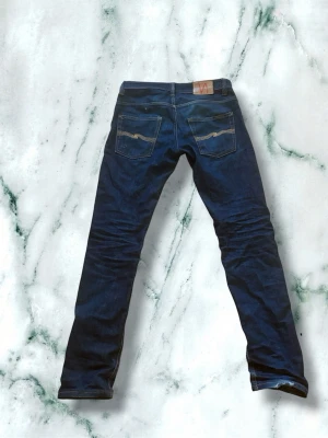 Blå slimfit jeans från Nudie Jeans - Riktigt najs slimfit jeans från nudie! Inte använda så mycket men har sjuk potential för slitningar. Dragkedjan i gylfen är lagad hos nudies egna butik då den var sönder innan. Storlek W32/L32