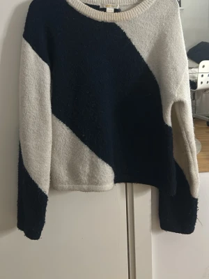 Stickad tröja med blockmönster - Snygg stickad tröja med blockmönster i mörkblått och vitt. Tröjan har rund halsringning och långa ärmar. Mjuk och skön kvalitet, perfekt för kyligare dagar. Finns inte att köpa på Gina längre 