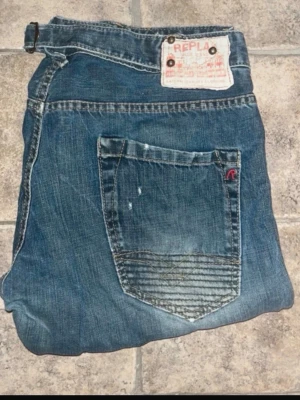 Replay jeans  - Snygga blå jeans från Replay med klassisk straight fit och coola slitningar på bakfickorna. Jeansen har fem fickor, tydliga kontrastsömmar och Replay-logga på bakfickan. Midja 41cm, längd 109cm. JAG SKICKAR EJ FLER BILDER NÄR JAG BÄR JEANSEN! för storleksguide hänvisar jag till måtten och för bättre inblick i passformen rekommenderar jag att googla på modellnamnet. Jeansen kan vara uppsydda utan att jag noterat det så kolla måtten noggrant :) s4
