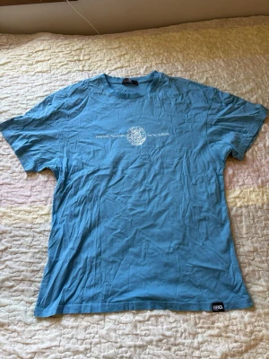 Blå t-shirt från BRO - Snygg blå t-shirt från BRO med vit text och grafiskt tryck på bröstet. Klassisk rund hals och korta ärmar. Tillverkad i mjuk bomull som känns skön mot huden. Perfekt för en avslappnad och enkel stil.