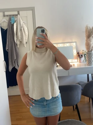 Beige ärmlös polotopp från Zara - Säljer en beige ärmlös polotopp från Zara. Toppen har en hög ribbad krage och är tillverkad i ett mjukt, stickat material. Perfekt att styla med kjol eller jeans för en clean och trendig look.