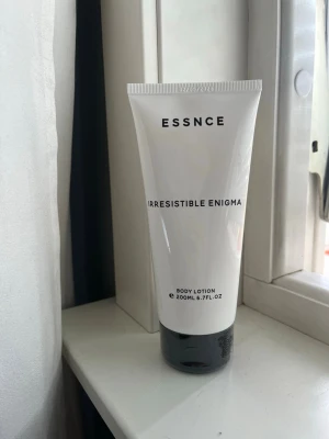ESSNCE Irresistible Enigma Body Lotion - Body lotion från ESSNCE i serien Irresistible Enigma. Tuben är vit med svart text och har en svart botten. Innehåller 200 ml (6.7 fl. oz) och passar perfekt för att återfukta huden. Enkel och stilren design som känns modern. Inspirerad av ”prada paradoxe”.