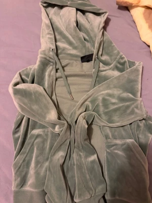 Grön velour hoodie Juicy Couture - Mjuk och lyxig ljusgrön velour hoodie från Juicy Couture. Klassisk modell med huva, dragsko och känguruficka framtill. Perfekt för en chill och trendig look. Materialet är glansigt och superbekvämt.                                                              ‼️kan byta också om det finns en grå i st S‼️