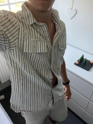 Randig skjorta från Zara relaxed fit - Säljer en vit och ljusblå randig skjorta från Zara i relaxed fit. Skjortan har långa ärmar, bröstficka och knappar framtill. Perfekt för dig som gillar en avslappnad och stilren look.