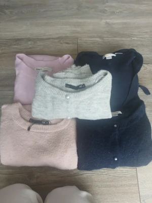Mörkblå omlottstickad tröja - Säljer en mörkblå stickad omlott-tröja med knytband i midjan och bred ribbstickad kant nedtill. Tröjan har långa ärmar och en klassisk omlott-design som ger en snygg siluett. Perfekt för dig som gillar stilrena och bekväma plagg.