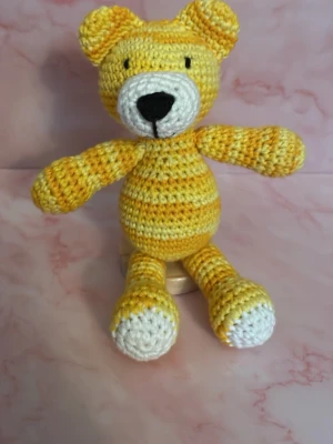 Gul virkad nallebjörn - Söt handvirkad nallebjörn i gult och vitt garn. Nallen har rund mage, långa armar och ben samt ett gulligt ansikte med svart nos och broderade ögon. Perfekt som dekoration eller present till någon du gillar. Sittande 11 cm