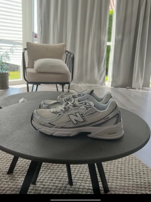 New Balance 530 vita sneakers - Säljer ett par New Balance 530 sneakers i vitt och silver med mesh och syntetdetaljer. Klassisk chunky sula och tydlig N-logga på sidan. Skorna har snörning och sportig retrostil som passar till många outfits.