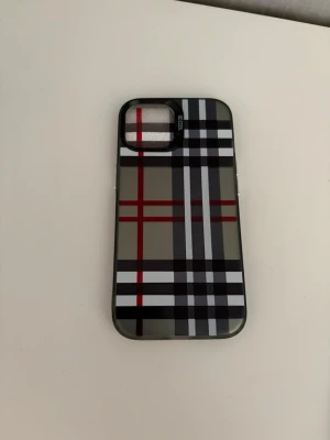 Rutigt mobilskal i flera färger - Snyggt mobilskal med klassiskt rutmönster i olika färger som beige, rött, blått och svart. Skalet har en stilren design med ränder i kontrasterande färger och är gjort i ett hårdare plastmaterial. Passar dig som vill ge mobilen en trendig look.