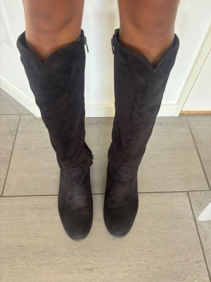 Svarta mocka boots  - Säljer ett par svarta knähöga stövlar i mjuk mockaimitation. De har rundad tå, 5 cm klack, dragkedja. Säljer endast via plicks köpknapp. 