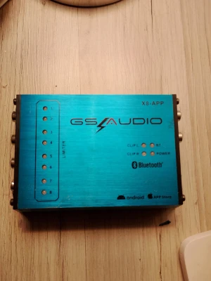 GS Audio X8-APP Bluetooth-modul - Säljer en blå GS Audio X8-APP Bluetooth-modul i metall. Enheten har flera anslutningar på sidorna, indikatorlampor för power, BT och clip, samt stöd för både Android och iOS via app. Perfekt för ljudsystem och smidig trådlös uppkoppling.