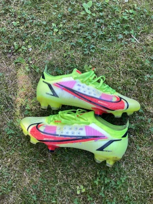 Nike Mercurial neon fotbollsskor - Säljer ett par Nike Mercurial vapor 14! Dessa skor är 9/10 i skicket i och med att det finns inget hål, dobbarna är i perfekt skick, de är inte smutsiga! Dessa skor går ej att på tag på bara begagnat  där utav är priset lite högre än vanligt! Skorna är såklart i elite modell och dessa är ett par skor som många anses vara snyggast på marknaden!