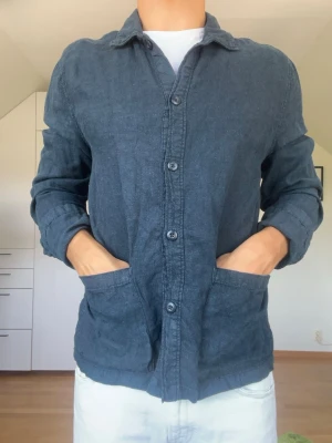Mörkblå overshirt i linne - Mörkblå overshirten från East West tillverkad i 100% linne. Strl S. Inga defekter. Modellen är 178 cm och väger 77 kg. Hör gärna av dig vid frågor!