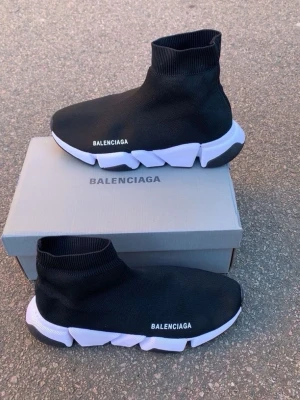 Balenciaga Speed Trainer svarta sneakers - Svarta Balenciaga Speed Trainer sneakers med vit chunky sula och stickad ovandel i textil. Strumpliknande passform och tydlig logga på sidan. Snygg och futuristisk design som sticker ut i mängden.