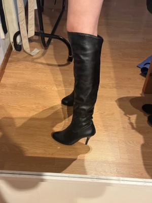 Svarta overknee stövlar med klack - Snygga svarta knähöga stövlar i läder med smal klack. I super bra skick, har en repa men ingenting som syns💕