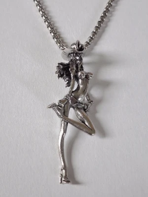 Silverfärgat halsband med cowgirl-hänge - Unikt halsband i silverfärgad metall med ett detaljerat hänge med sexy cowgirl med hatt och boots. Kedjan är av klassisk modell och hänget har en cool, lekfull design som sticker ut. Perfekt accessoar för dig som gillar statement-smycken. Materialet rostfritt stål. 