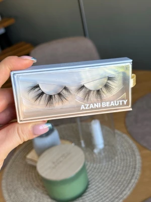 Azani Beauty lösögonfransar volym - Säljer ett par fluffiga och voluminösa lösögonfransar från Azani Beauty. Fransarna är svarta, har en dramatisk och fyllig form med långa, separerade strån för en intensiv look. Förpackningen är genomskinlig med holografisk effekt.
