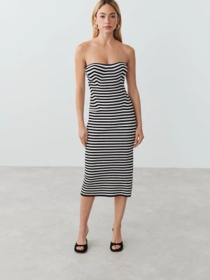 Randig axelbandslös klänning - Säljer en svartvit, ribbad och axelbandslös klänning med figursydd passform från gina . Klänningen har ett randigt mönster och är midilång, vilket ger en stilren och trendig look. 💕
