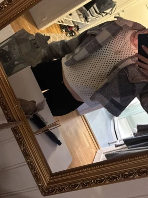 Vit stickad croppad topp - Säljer en vit stickad croppad topp med hålmönster och rund hals. Toppen är kort i modellen och har en loose passform, perfekt att styla över ett linne eller bralette. Superenkel att matcha till olika outfits!