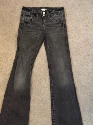 Grå bootcut jeans strl 152  -  Säljer ett par grå fina lågmidjade bootcut jeans med dubbel knapp. De har används några gånger och är i bra skick.