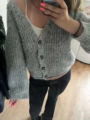 Trendig grå stickad kofta från Zara - Mysig grå stickad kofta från Zara med stora knappar framtill och v-ringad hals. Storleken som ni ser på bilden är 152 men skulle säga att den är som en xs då den känns lite overzized eftersom den är stretchig och mjuk⭐️