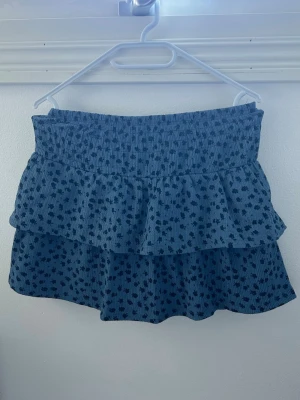 Blå Zara kjol - Oanvänd Zara kjol i blå färg med mörkblåa blommor som detaljer, stretchig så kan även passa M! Passar perfekt till sommaren 