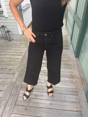 Vida svarta jeans från TOTÉME - Säljer ett par svarta jeans från TOTÉME med hög midja och vida, croppade ben. Har aldrig använt. Perfekta till sneakers eller sandaler för en cool look.