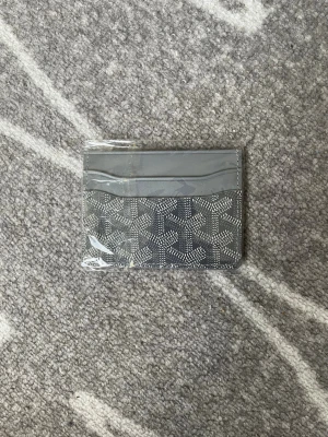 Grå kortfodral  - Snyggt grått kortfodral från med det klassiska mönstret i vitt och grått. Fodralet har flera fack för kort och är gjort i ett tåligt material med en lyxig känsla. Perfekt för dig som vill ha något stilrent och exklusivt i fickan.