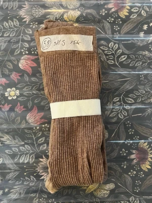 Bruna ribbade tights - Säljer ett par bruna ribbade tights med mjuk känsla och stretchigt material. Tightsen har en klassisk ribbad struktur och passar perfekt för dig som gillar en enkel men snygg stil. 