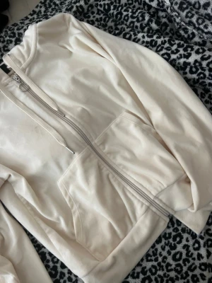Beige zip hoodie med fickor - Snygg beige hoodie med dragkedja framtill och stora fickor. Har huva med dragsko och ribbade muddar vid ärmslut och nederkant. Perfekt för en avslappnad look och enkel att matcha med andra plagg. Mjuk och skön bomullsblandning.