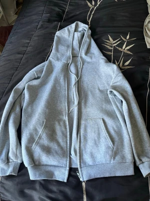 Ljusgrå zip hoodie med fickor - En enkel och stilren ljusgrå hoodie med dragkedja framtill, två stora fickor och justerbar huva med snören. Tillverkad i mjukt sweatshirtmaterial och har ribbade muddar vid ärmar och nederkant. Perfekt för en avslappnad look. använd några få gånger