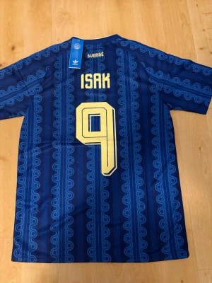 Isak #9 – Sverige Borta (storlek L) - Isak #9-tryck. Sverige Borta (blå). Storlek L. Helt ny och aldrig använd. Skickas snabbt 🚚💨  Mått (L): Halvt bröstmått 55 cm • Längd 76 cm • Ärmbredd 24 cm • Axelbredd 46 cm • Ärmlängd 41 cm • Manschett 20 cm.  🔥 Fan Edition – normal passform. 🇸🇪 Sverige landslag.  📩 Frågor eller prisförslag? Skicka gärna ett meddelande! 🛍 Bundle-rabatt upp till 20% 💰 📦 Skickas samma eller nästa dag 🌟