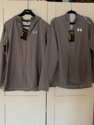 Grå vindjacka från Under Armour - Säljer båda två jackor . Om ni vill bara köpa en av de så har jag en annan annons uppe i min profil. Hade rekommenderat att köpa de å dela priset med än vän så får ni varsen jacka