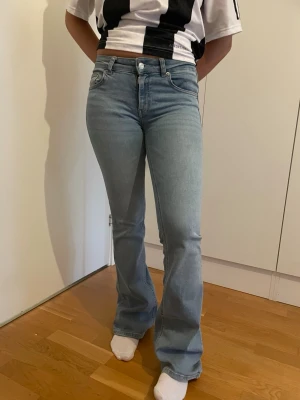 Ljusblå bootcut jeans - Säljer ett par ljusblå bootcut jeans med klassisk femficksmodell och normalhög midja. Jeansen har en snygg tvätt och lätt utsvängda ben som ger en retrovibe. Perfekta till sneakers eller boots och passar till många olika stilar.