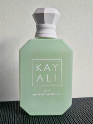 Kayali - Yum Pistachio Gelato EdP 50ml - Se mängd enligt bild. Locket är lite snett men inget som påverkar funktionen och den läcker inte.  Toppnoter: Italian Bergamot, Pistachio Gelato, Hazelnut, Sweet Rum & Cardamom Hjärtnoter: Geranium, White Peony, Muguet, Jasmine, Raspberry, White Peach & Pear Basnoter: Whipped Cream, Marshmallows, Cotton Candy, Turkish Delight Accord, Cocoa, Cedarwood, Sandalwood & Tonka  Läs mer om doften här: https://www.fragrantica.com/perfume/Kayali-Fragrances/Yum-Pistachio-Gelato-33-79846.html