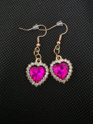 Hjärtfomade örhängen med rosa sten - Snygga handgjorda örhängen i guldton med hjärtformad, klarrosa sten i mitten. Runt stenen sitter små gnistrande stenar som ger extra bling. Perfekta för dig som gillar statement-smycken och vill sticka ut. Krokar i metall för enkel användning.