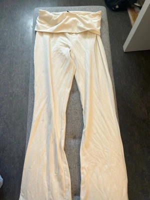 Vita yoga pants  - Säljer ett par vita yogapants med bred, vikbar linning och raka ben. Byxorna är tillverkade i ett mjukt och stretchigt material som känns skönt mot huden. Perfekta för chill dagar hemma eller när du vill ha en avslappnad look.
