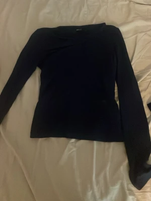 Mörkblå långärmad tröja - En enkel och stilren mörkblå långärmad tröja med rund halsringning. Tröjan har en smal passform och är perfekt att matcha med jeans eller kjol. Materialet känns mjukt och stretchigt, vilket gör den bekväm att bära hela dagen.