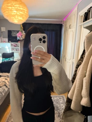 Vit ribbstickad bolero - Säljer en vit ribbstickad bolero med långa ärmar. Perfekt att slänga över en klänning. Materialet är mjukt och stretchigt, vilket gör den bekväm att bära. Enkel och stilren design utan synliga knappar eller dragkedjor.