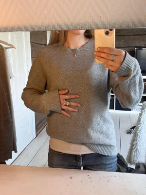Grå stickad tröja från vero moda - Mysig grå stickad tröja från H&M med rund halsringning och långa ärmar. Tröjan har ribbade muddar vid ärmslut och nederkant, och är tillverkad i mjukt material som passar perfekt till jeans eller kjol.  