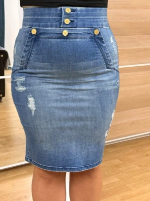 Blå denimkjol med guldknappar - Snygg blå denimkjol med hög midja och dekorativa guldknappar framtill. Kjolen har slitna detaljer och en figurnära passform som ger en modern look. Perfekt för dig som gillar jeansstil och vill ha något trendigt i garderoben. Köpt från butiken bebe i usa är ej använd