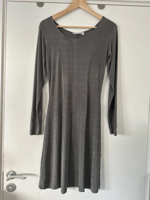 H&M - Grå långärmad klänning - storlek XS / S - Fin grå klänning från H&M i storlek XS / S / 34-36 med långa ärmar och rund halsringning. Klänningen har en smickrande passform med en lätt utsvängd kjol som slutar vid knät. Den är designad med diskreta sömmar som framhäver figuren. Klänningen är enkel att styla för både vardag och fest. 