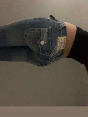 Blå True Religion jeans med brodyr - Säljer ett par blåa true religon jeans med vingdetaljer där bak. Modellen är joey och storleken är W23. Säljer dem eftersom dem tyvärr inte kommer till andvändning längre.