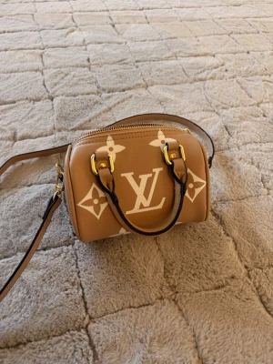 Louis Vuitton beige monogram handväska - Säljer en beige handväska från Louis Vuitton med klassiskt vitt monogrammönster och guldfärgade metalldetaljer. Pris går att diskuteras vid möte i göteborg eller snabbköp