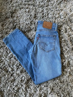 Levi's ljusblå raka jeans - Säljer ett par klassiska ljusblå jeans från Levi's med rak passform. Jeansen har fem fickor, bälteshällor och den ikoniska läderlappen bak i midjan. Perfekta till vardags för en avslappnad och tidlös stil.
