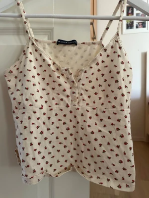Blommig linnetopp med knappar - Söt linnetopp från Brandy Melville i ljusbeige med små röda blommor. 