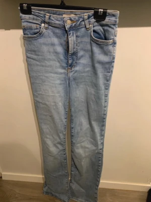 Ljusblå bootcut jeans - Säljer ett par ljusblå jeans med bootcut passform. Jeansen har hög midja och stängs med knapp och dragkedja. Perfekta för en avslappnad och trendig look.