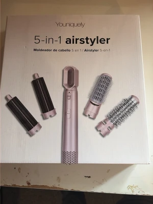Youniquely 5-i-1 airstyler rosa - Multifunktionell 5-i-1 airstyler i ljusrosa med fem utbytbara stylinghuvuden för hår: två locktänger och två rundborstar samt ett fönmunstycke. Perfekt för att skapa olika frisyrer och volym. Modern design med enkel knappkontroll. Den är andvänd 2 gånger men tog av plasten på 3/5 av verktygen säljer pågrund av att den inte andvända. Ny pris 389