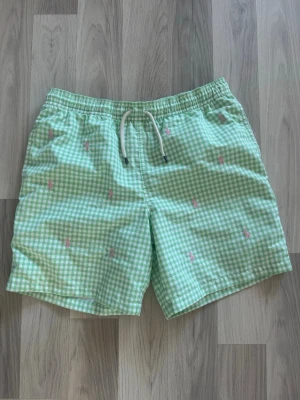 Ralph Lauren badbyxor - Grönrutiga badbyxor från Ralph Lauren med den rosa loggan på. Storlek XL youth 18-20 vilket motsvarar Small. Utmärkt skick, knappt använda. Hör av er vid frågor! 