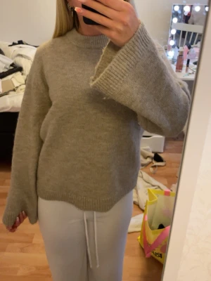 Beige stickad tröja  - Mysig beige stickad tröja från Gina tricot med oversized passform och breda, långa ärmar. Tröjan har rund halsringning och ribbade muddar vid ärmslut och nederkant. Perfekt att dra över nu på sommaren, men också mysigt i hösten. använd fåtal gånger och säljs på grund utav att jag inte tycker att den passar mig(färgen asså) . 